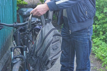 one man hangs gray backpack bag on black bicycle handlebar on spring street