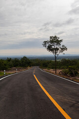 Aerial view of a long winding road from Phu Phan Mountains to Kut Bak, Sakon Nakhon, Thailand, surrounded by lush nature and clear sky, travel and landscape concept.