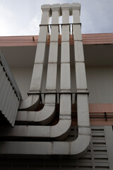 Four modern air ventilation towers featuring sharp angular cutouts and dimensional shapes against a clear sky. Minimalist industrial architecture.
