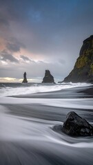 Black sand beach at sunset with dramatic rocks