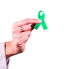 Woman’s hand holding a green ribbon over a transparent background. Symbol of mental health...
