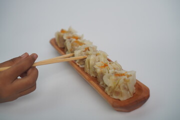 Hand Holding Dim Sum with Chopsticks on White Background