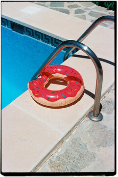 donut-shaped swim ring next to a pool, 35mm