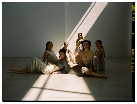Group of six models posing in natural light in a minimalist spac