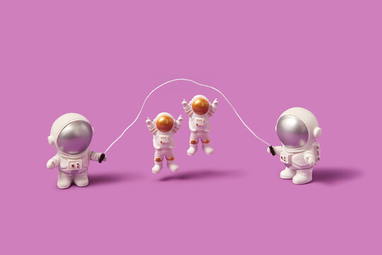 Astronauts jump rope on pink background