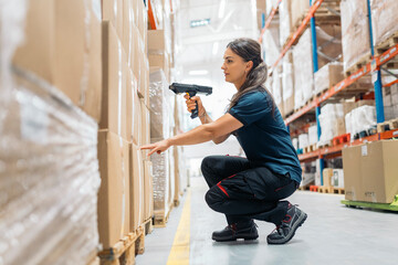 Logistic worker scanning packages in warehouse with barcode reader