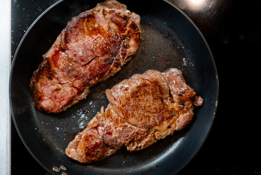 Grilled beef steaks searing in a hot frying pan