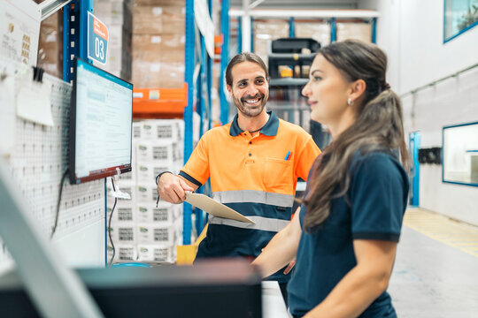 Logistic workers checking inventory and using computer in warehouse