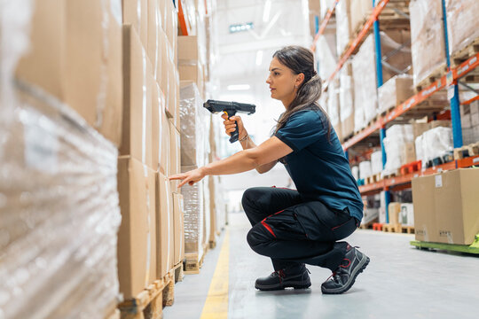 Logistic worker scanning packages in warehouse with barcode reader