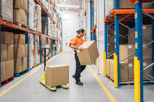 Logistic worker carrying cardboard box in warehouse