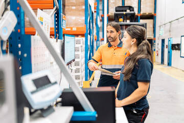 Warehouse workers discussing logistics using computer and clipboard