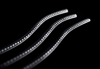 Three wavy, light gray plastic strips on black background
