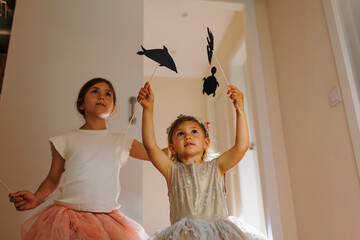 Two girls playing with animal shadow puppets at home