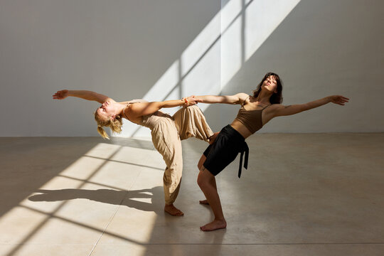 Two dancers express motion in studio with natural light