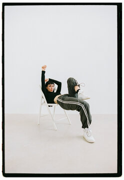 Model poses casually on chair in minimalist studio setting
