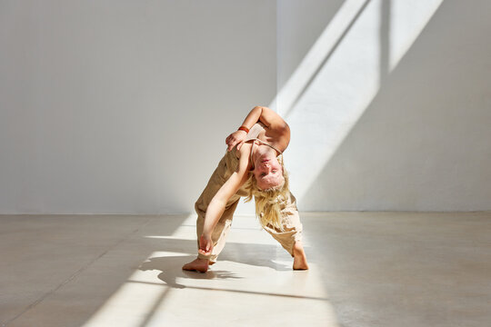 Dancer expresses fluid movement in bright studio light