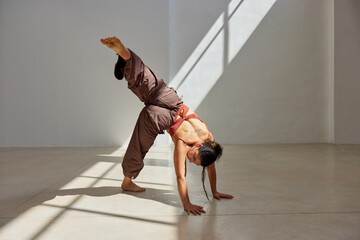 Dynamic dance pose in a sunlit studio