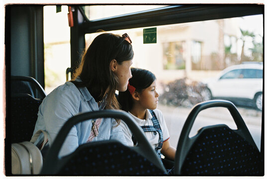 Mother and daughter riding bus and looking at window