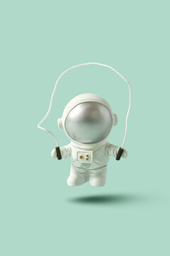 Single astronaut statue skipping rope on mint background