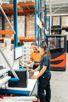 Warehouse workers managing inventory using computer and checklist