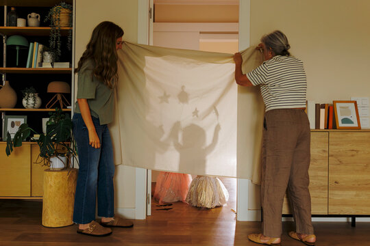 Mother and grandmother revealing shadow puppet show for little girls