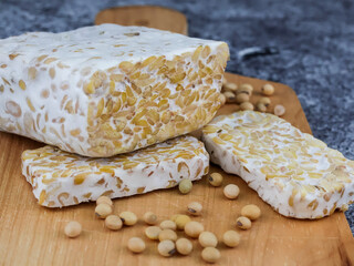 Sliced of Tempeh or tempe and soybeans on cutting board. Tempeh is a traditional Indonesian food made from fermented soy beans. 