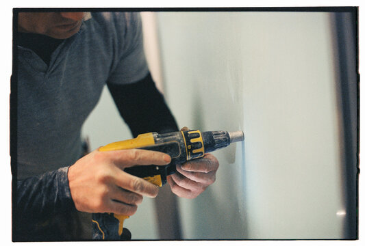 Skilled Worker Using Screw Gun for Drywall Installation