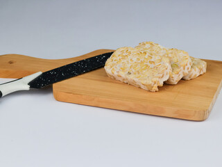 Top view Sliced of Tempeh or tempe on cutting board and knife. Tempeh is a traditional Indonesian food made from fermented soy beans. 