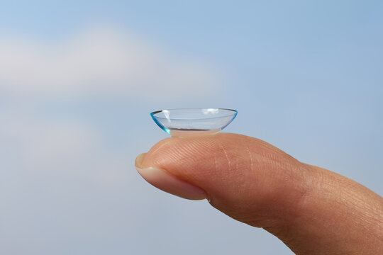 Contact lens on fingertip with sky background