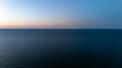 Calm ocean horizon at dusk with soft pastel sky reflections.