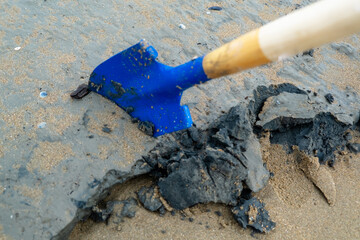 Blue shovel digging into wet sand and clay on beach.