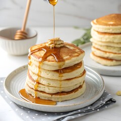 Delicious stack of fluffy pancakes being drizzled with golden honey