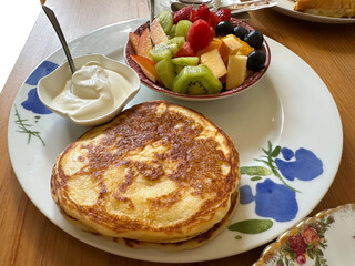 Delicious breakfast plate featuring fluffy pancakes served with fresh fruit salad and creamy yogurt on a rustic wooden table, showcasing a vibrant and inviting morning meal experience