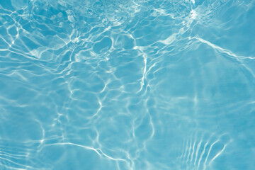 Blue water with ripples on the surface. Defocus blurred transparent blue colored clear calm water surface texture with splashes and bubbles. Water waves with shining pattern texture background.