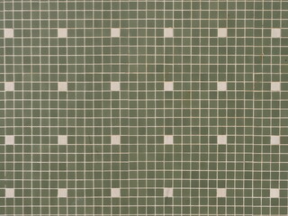 Green mosaic wall consisting of small square tiles. Occasionally, lighter, almost white tiles are...