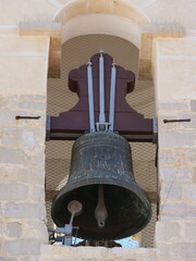 Obraz premium Large church bell suspended in a bell tower. The clapper inside the bell and the mounting structure that holds the bell in place are visible. A protective net against birds surrounds the bell