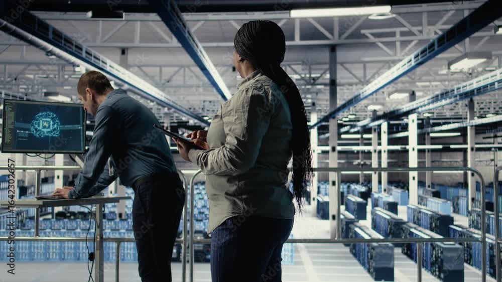 Poster it expert monitors server farm activity using tablet while walking on industrial platform. data cent
