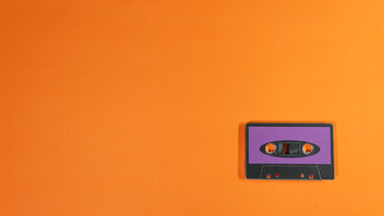 Retro Purple Cassette Tape on Orange Background Flat Lay