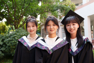 Close up of three happy asian graduates in the sunny campus