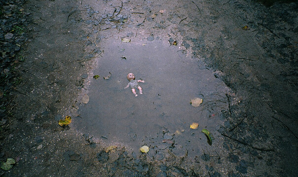 DIrty old baby dol in the puddle