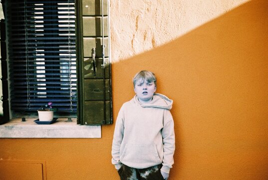 Child in Hoodie Against orange Wall