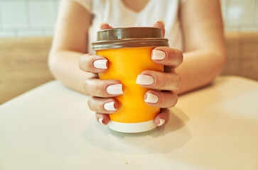 Woman holding a cup of coffee with a yellow lid