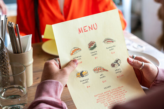 Close-up  hands holding sushi menu 