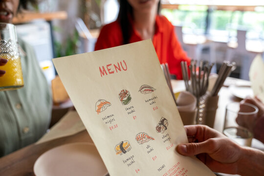 Close-up of sushi menu held by customer
