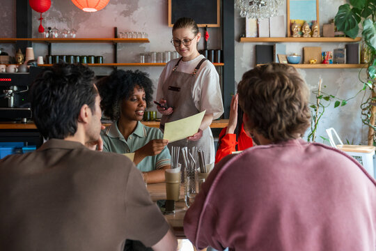 Woman showing menu to waitress in cafe