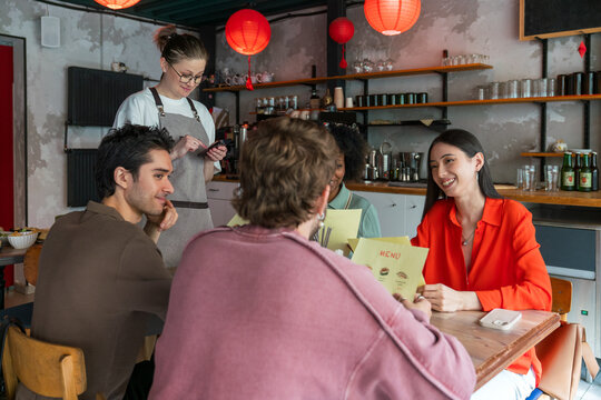 Waitress taking orders from friends in cafe