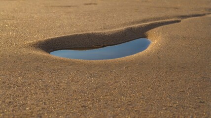 Small puddle of water on the beach sand