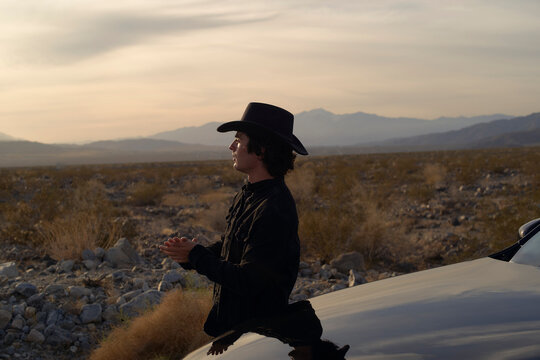Man in Cowboy Hat Reflecting During Sunset in a Desert Landscape