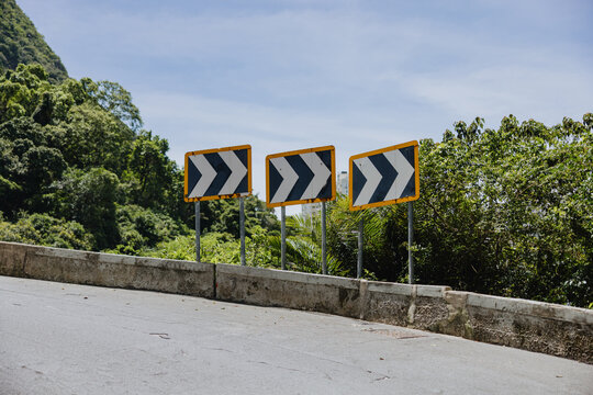 Curved Road Signs Indicate Sharp Turn Ahead in Lush Landscape