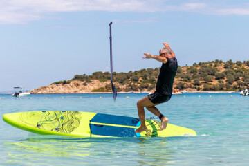 Beginner sup surfer  losing balance on paddle board. A mature man falling down off the SUP board...